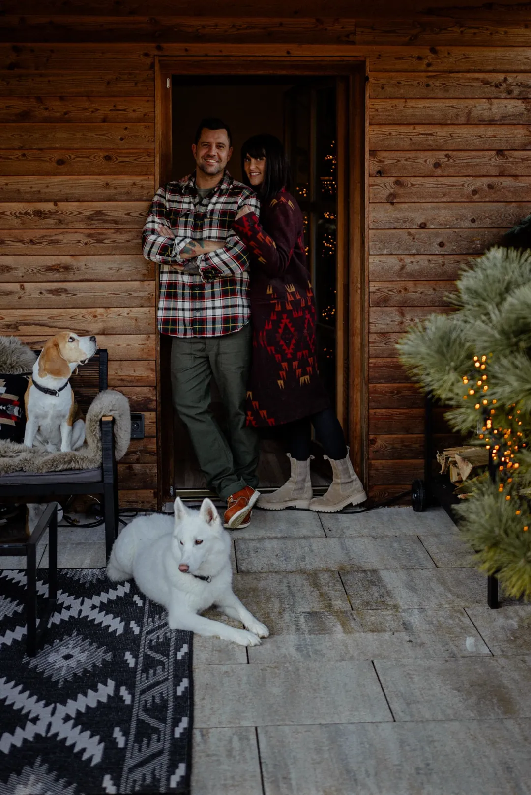 Ben Kauer und seine Partnerin im Türrahmen ihres Landhauses, im Vordergrund Beagle und weißer Husky